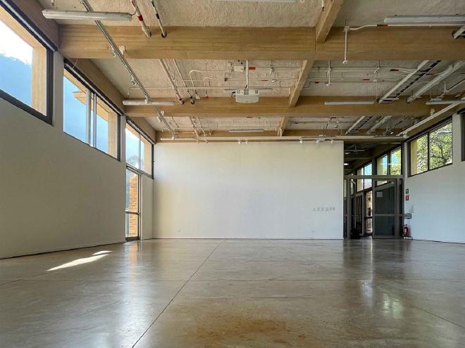 The empty exhibition space, with white walls, large windows and a ceiling projector, that La traición necesaria describes and recreates