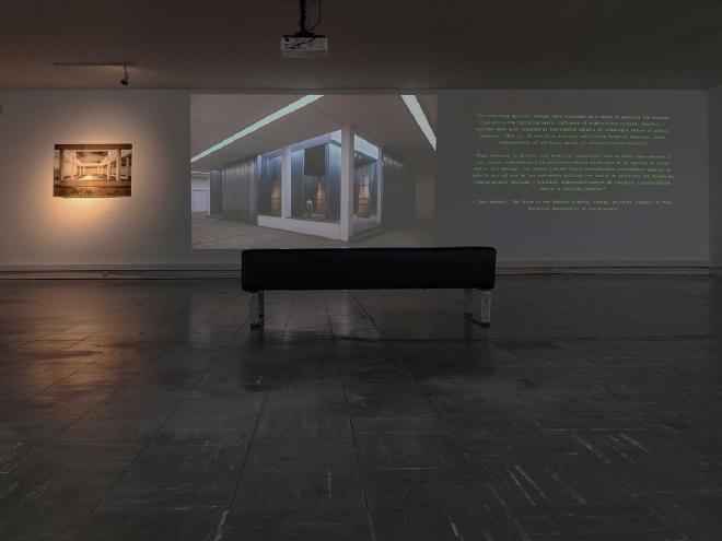 Exhibition view of Visiones inestables: a projected AI-generated image of the museum, a projected quote and a lit photograph in a dark gallery