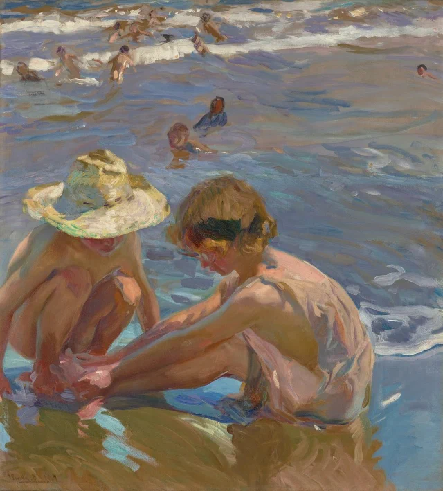 Two children crouching in shallow sunlit water, one tending the other's foot
